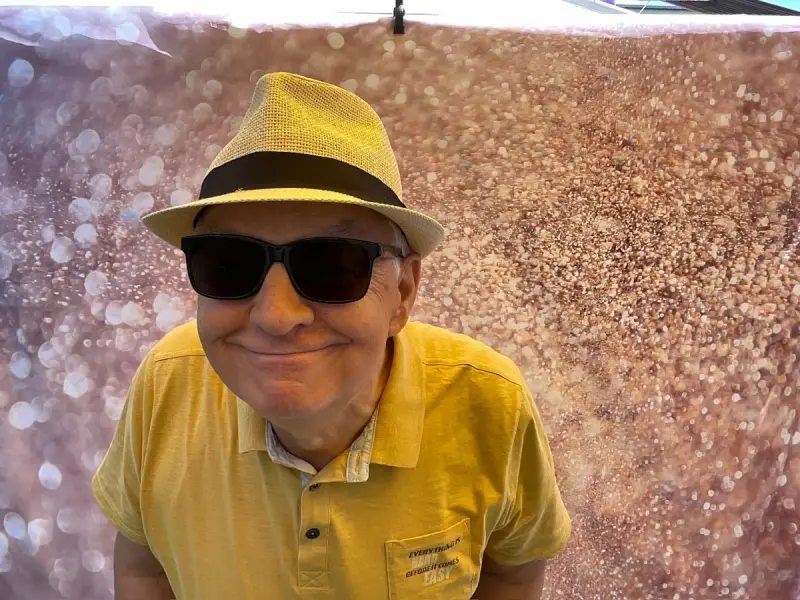 Fotobox Gast mit Hut und Sonnenbrille vor Glitzer-Leinwand