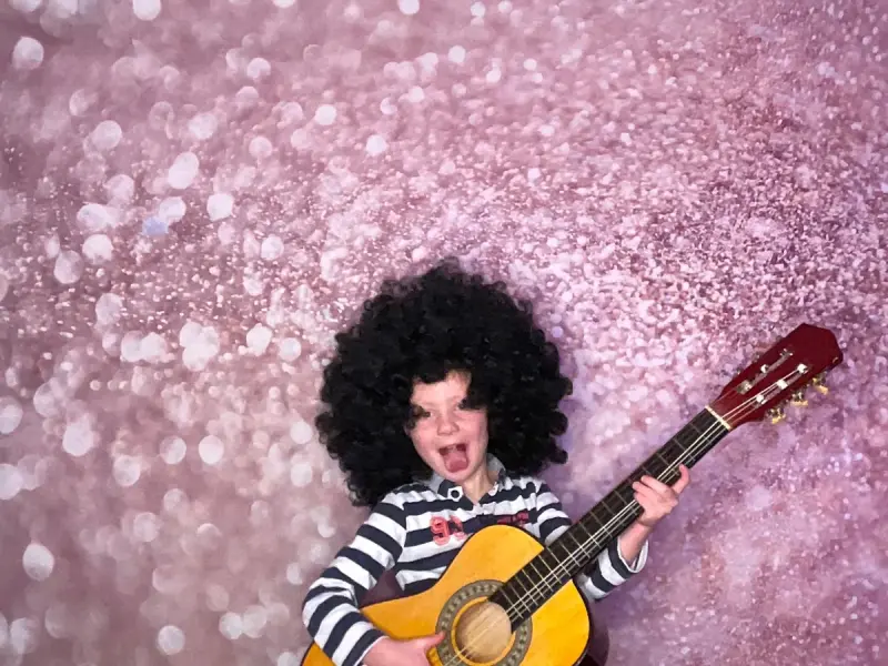 Kind mit Perücke und Gitarre vor Fotobox