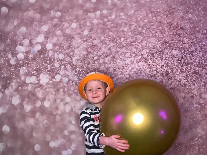 Kind mit Hut vor Glitzer-Leinwand